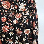 Close-up of fabric with a floral pattern featuring red, white, and beige flowers on a black background, ideal for fashion and clothing design.
