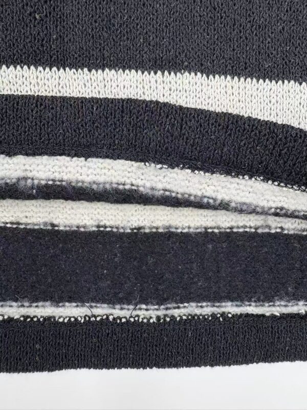 Detailed close-up of black and white striped fabric showing texture and pattern, ideal for fashion or textile design.