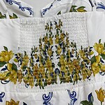 Elegant white summer dress with vibrant yellow floral print and smocked waist, perfect for warm weather and casual outings.