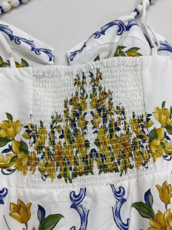 Elegant white summer dress with vibrant yellow floral print and smocked waist, perfect for warm weather and casual outings.
