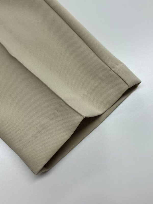 Close-up of beige blazer fabric showing smooth texture and tailored stitching for stylish professional wear.