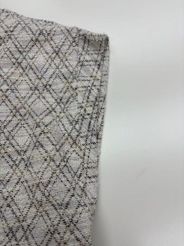 Close-up of a fabric with a detailed geometric pattern in neutral tones, suitable for fashion and apparel design.