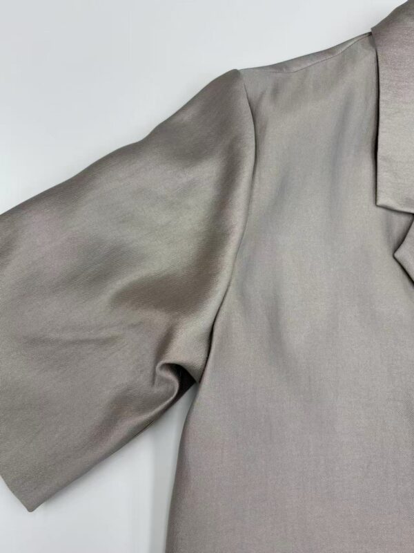 Close-up of a luxurious satin blouse with a tailored collar and puffed sleeve, perfect for formal or evening wear.