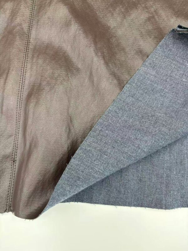 Close-up of a brown leather surface with a gray fabric lining, showing texture and stitching details.