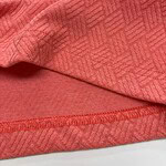 Close-up of red fabric with geometric pattern, showcasing texture and detailed stitching, ideal for fashion and textile design.