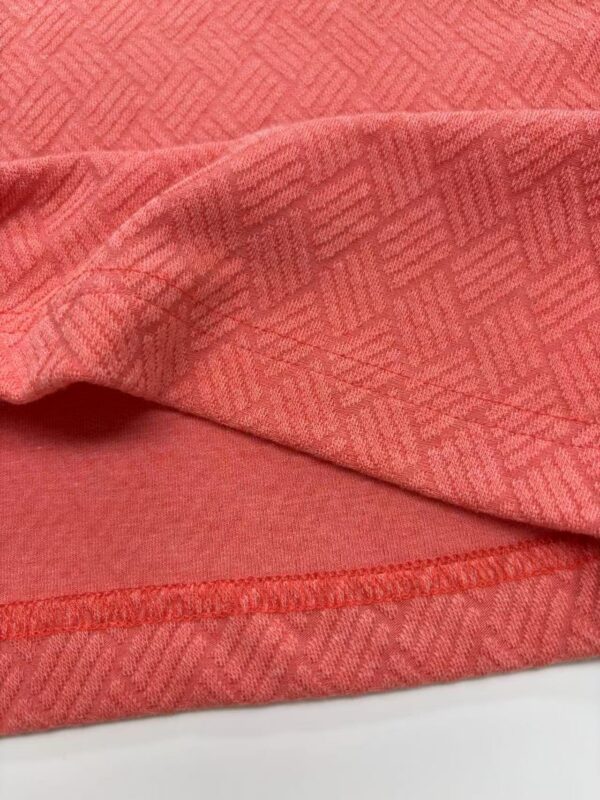 Close-up of red fabric with geometric pattern, showcasing texture and detailed stitching, ideal for fashion and textile design.