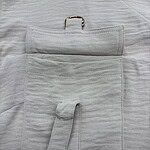 Close-up of a white medical pouch with a pocket, strap, and metal ring, placed on a white fabric surface, used for organizing medical tools.