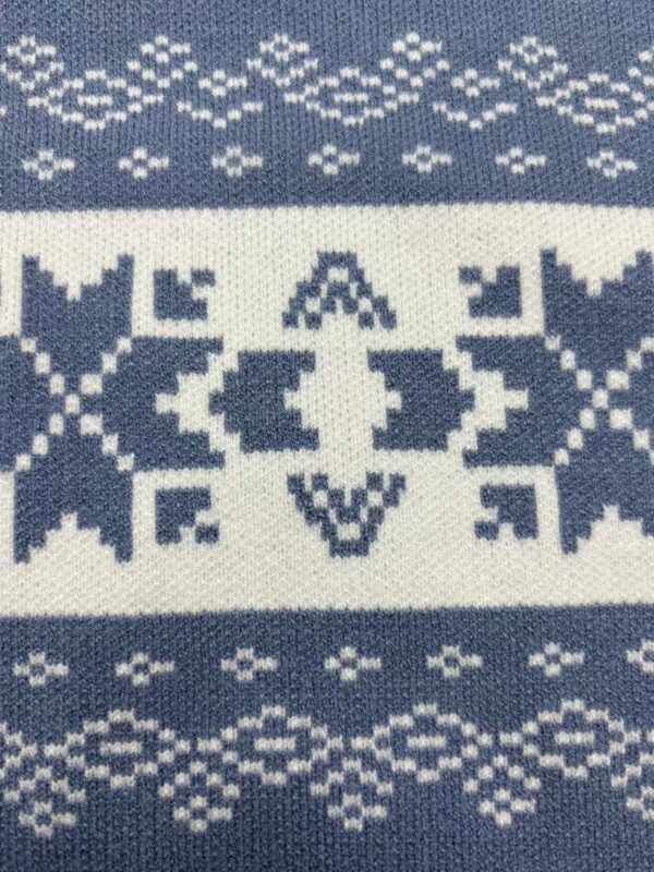 Close-up of a winter knit sweater featuring traditional Nordic patterns in white on a blue background, showcasing detailed geometric designs.