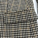 Close-up of a classic houndstooth wool coat with a detailed pocket and tailored design, perfect for fall and winter fashion.