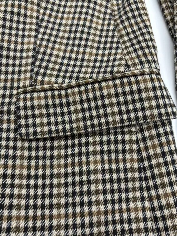 Close-up of a classic houndstooth wool coat with a detailed pocket and tailored design, perfect for fall and winter fashion.