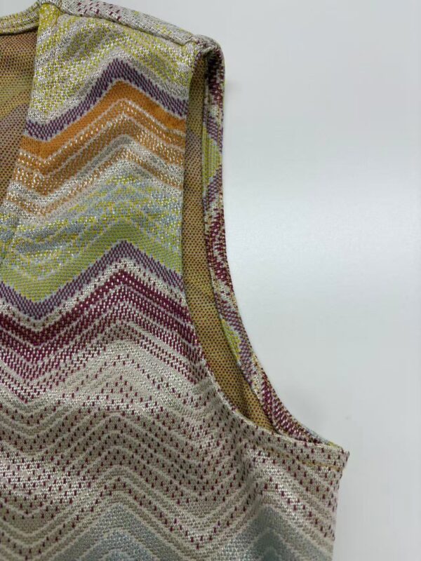 Close-up of a vibrant, zigzag patterned textile with multicolored threads, showcasing intricate craftsmanship and detailed weaving.