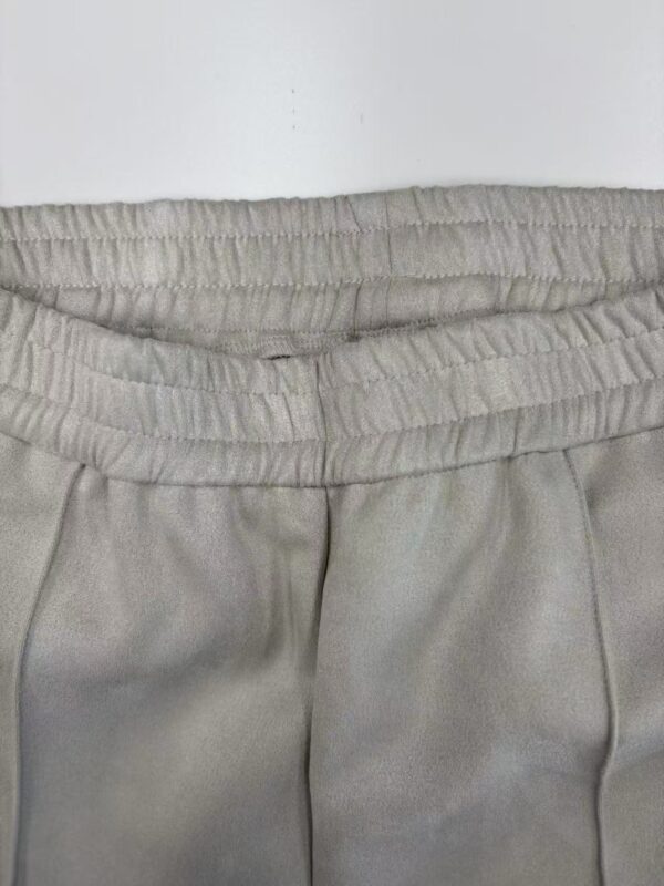 Close-up of beige casual pants with elastic waistband, suitable for everyday wear and relaxed fashion styles.