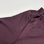 Close-up of a luxurious burgundy satin blouse with a high collar and subtle sheen, perfect for formal or evening wear.
