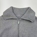 Close-up of a gray zip-up sweater with a ribbed collar, suitable for casual or athletic wear, made from comfortable knit fabric.
