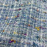Close-up of vibrant tweed fabric with multicolored threads and textured weave, ideal for high-end fashion and clothing accessories.
