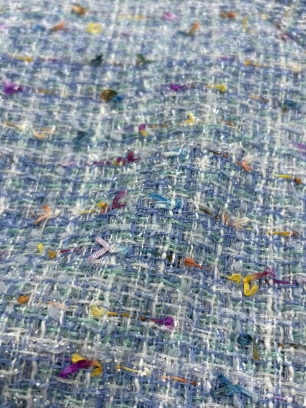Close-up of vibrant tweed fabric with multicolored threads and textured weave, ideal for high-end fashion and clothing accessories.