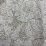 Close-up of linen fabric featuring a detailed leaf pattern in neutral tones, ideal for fashion and home decor projects.
