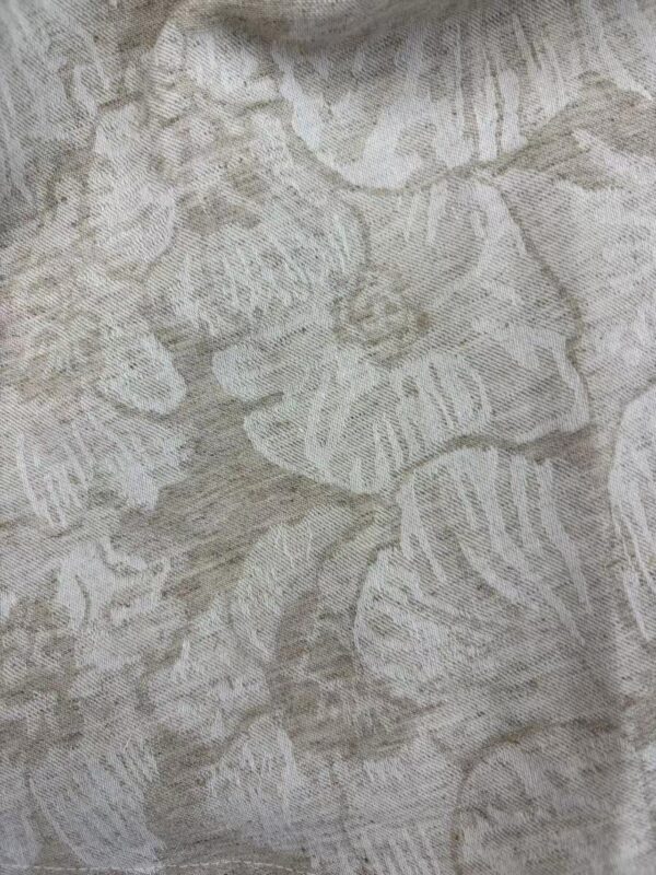 Close-up of linen fabric featuring a detailed leaf pattern in neutral tones, ideal for fashion and home decor projects.