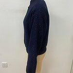 Close-up of a navy blue knitted sweater displayed on a mannequin, showcasing its textured fabric and cozy design.