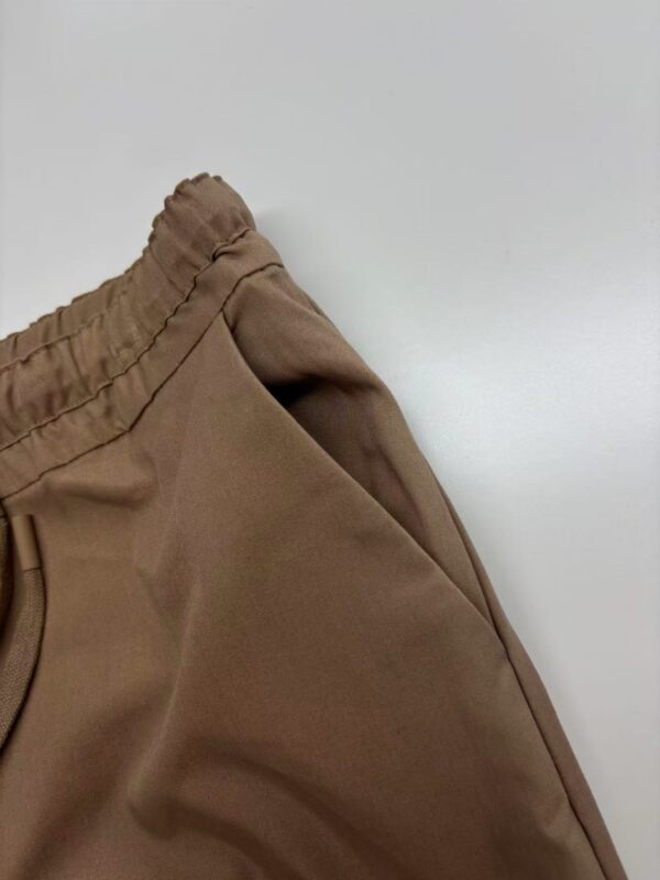 Close-up of brown jogger pants with elastic waistband, made of comfortable fabric, suitable for casual wear and sports activities.