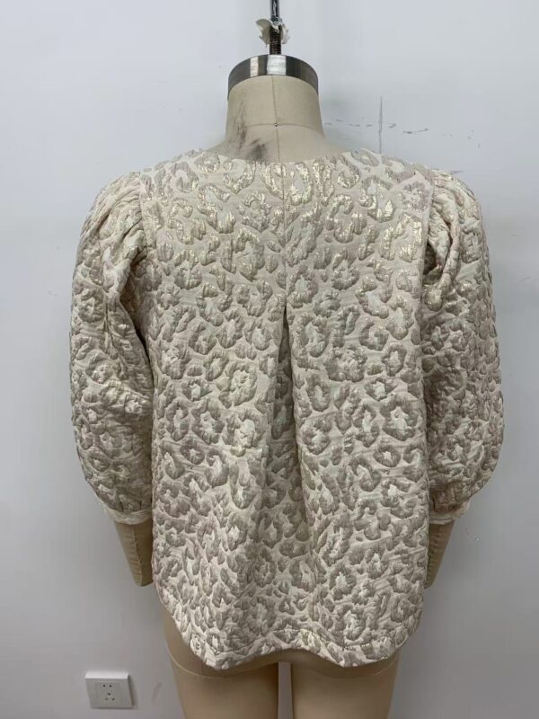 Elegant cream-colored women's jacket with textured pattern and puffed sleeves, suitable for formal or special occasions.