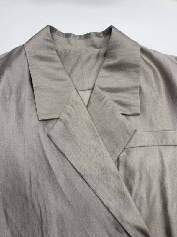 Close-up of a beige satin blazer with a notched lapel, tailored fit, and smooth fabric, perfect for stylish office wear or formal occasions.