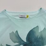 Light blue women's T-shirt with a large floral print in darker blue shades, casual and stylish for everyday wear.