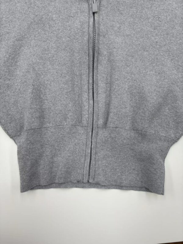 Close-up of a gray zip-up hoodie made of soft fabric, featuring a front zipper and ribbed cuffs, ideal for casual wear and comfortable style.