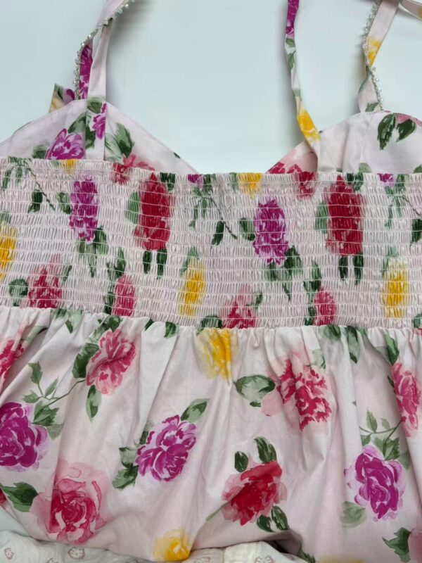 Beautiful floral summer dress with pink, purple, and yellow flowers on a light background, featuring adjustable straps and smocked bodice for a comfortable fit.