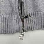 Detailed view of a grey hoodie with a silver zipper and ribbed hem, showcasing casual fashion and comfortable fabric.