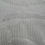 Close-up of intricate lace fabric with wave-like patterns, ideal for fashion and textile design.