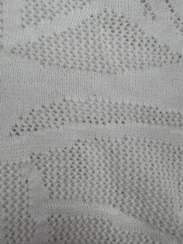 Close-up of intricate lace fabric with wave-like patterns, ideal for fashion and textile design.
