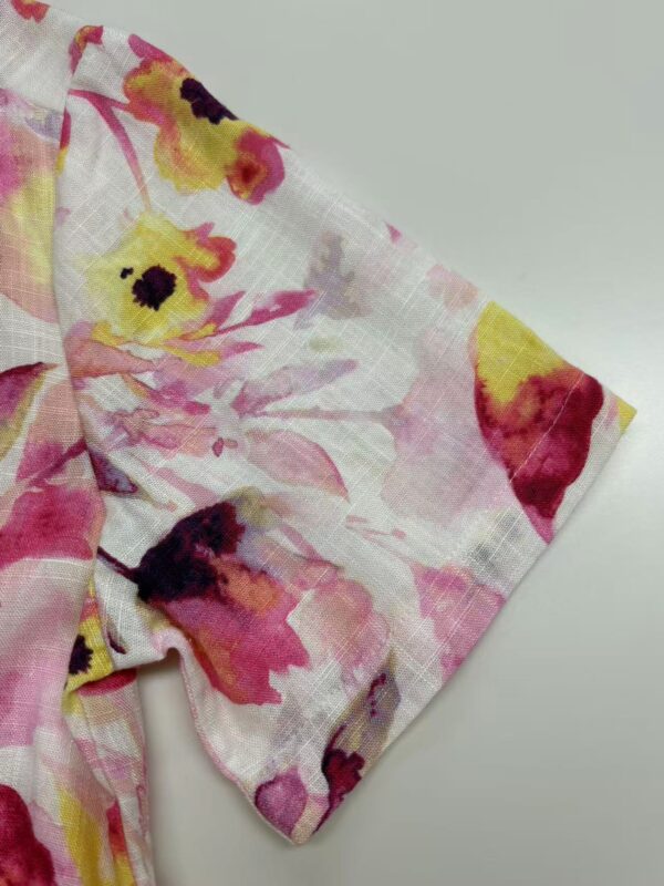 Close-up of floral fabric with pink, yellow, and black accents, suitable for clothing or accessories.