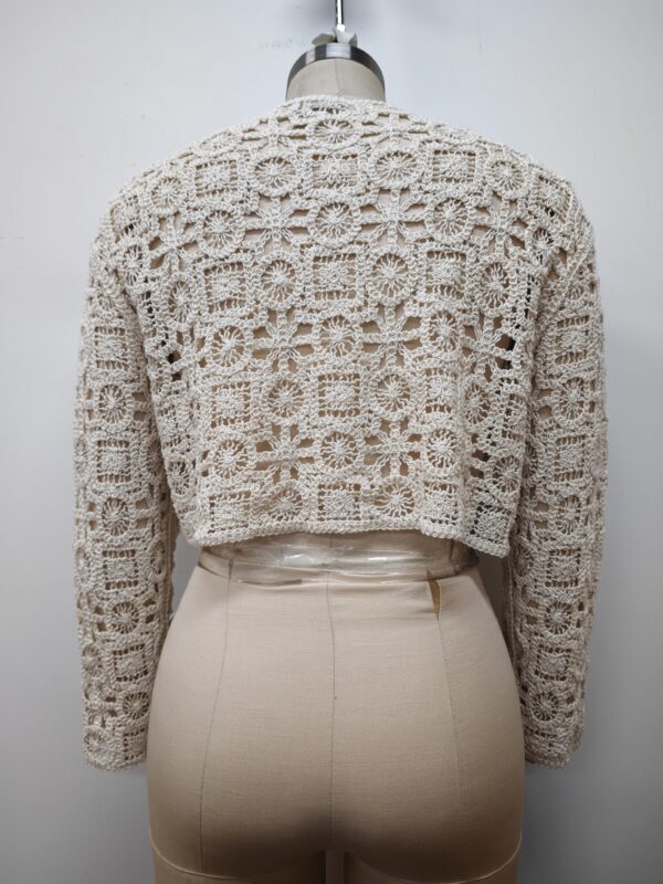 Close-up of a beige crochet knit sweater displayed on a mannequin, showcasing intricate floral and geometric patterns for a stylish look.