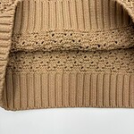 Close-up of a beige knitted beanie hat with ribbed and textured patterns, suitable for cold weather and winter fashion.