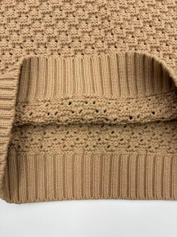 Close-up of a beige knitted beanie hat with ribbed and textured patterns, suitable for cold weather and winter fashion.