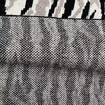 Close-up of animal print fabric with zebra and snake patterns in black, white, and gray tones, showcasing detailed textile design.