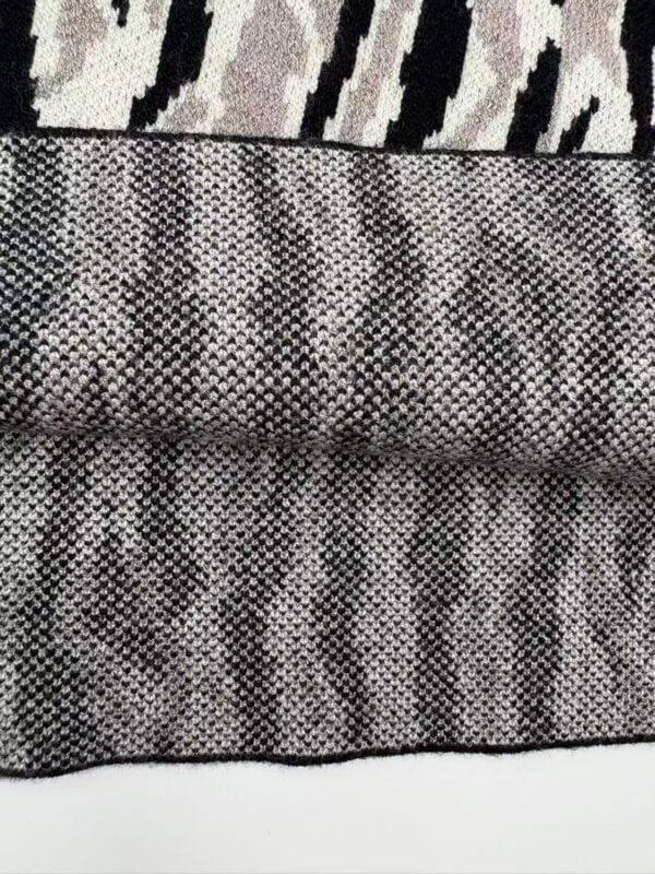Close-up of animal print fabric with zebra and snake patterns in black, white, and gray tones, showcasing detailed textile design.