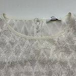 Close-up of delicate white lace fabric with intricate floral patterns, suitable for wedding dresses and evening gowns.