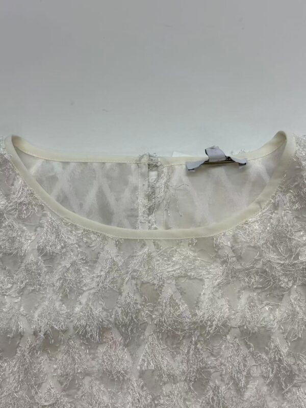 Close-up of delicate white lace fabric with intricate floral patterns, suitable for wedding dresses and evening gowns.