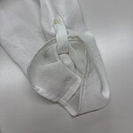 Close-up of a white dress shirt sleeve with a buttoned cuff, showcasing fine fabric and stitching for formal wear.