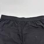 Close-up of black men's fashion shorts with elastic waistband and metal eyelets, suitable for casual or athletic wear.