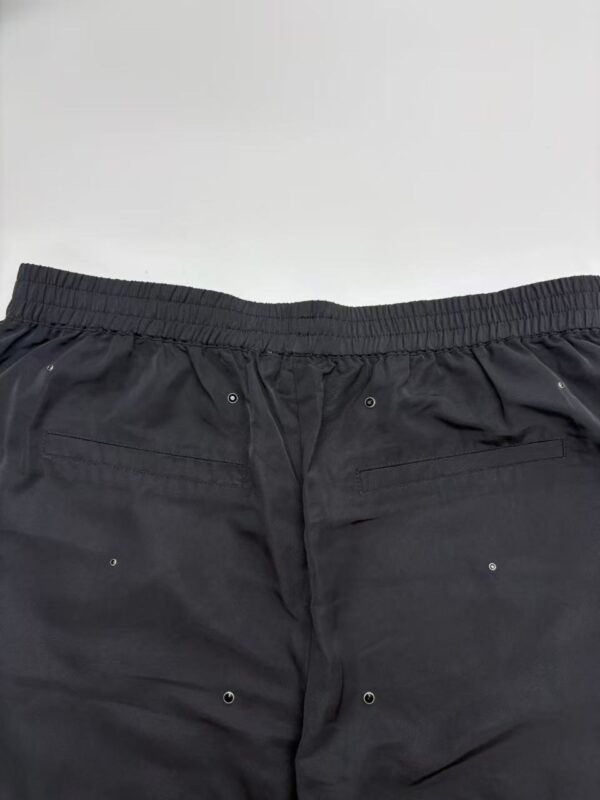 Close-up of black men's fashion shorts with elastic waistband and metal eyelets, suitable for casual or athletic wear.