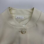 Close-up of a cream-colored women's button-up shirt with a single button and a V-neck collar, perfect for casual or formal wear.