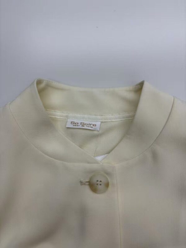 Close-up of a cream-colored women's button-up shirt with a single button and a V-neck collar, perfect for casual or formal wear.
