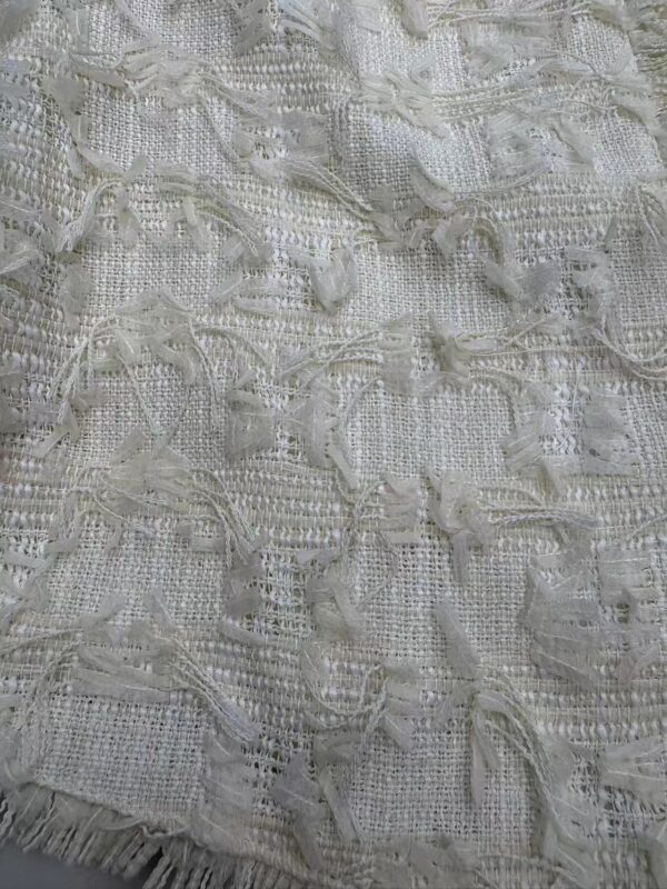 Close-up of intricate white lace fabric with textured patterns and delicate details, ideal for fashion and dressmaking.