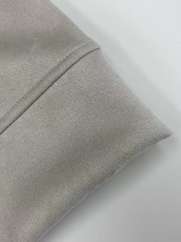 Close-up of beige fabric with smooth texture and fine stitching, ideal for fashion and apparel design.