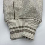 Close-up of beige sweatshirt cuff featuring ribbed knit and two horizontal stripes, showcasing casual fashion style.