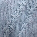 Close-up of light gray knitted fabric with textured pattern and frayed edges, showcasing soft and cozy material suitable for sweaters or scarves.