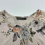 Close-up of a women's top with floral print, lace details on shoulders, and a round neckline, perfect for casual or semi-formal wear.